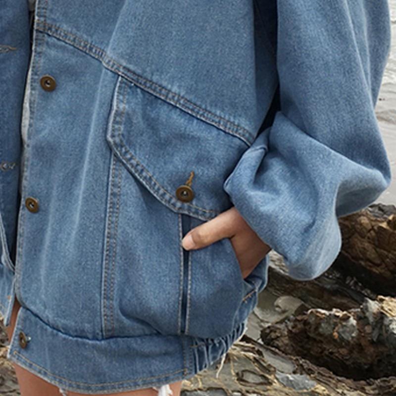 R&G Boutique Esther denim jacket hanging on a wooden hanger, showcasing classic blue denim with button closure and chest pockets.